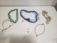 Six jewelry pieces including five necklaces and one stud earring arranged on a white surface.