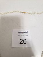 Image showing full length of pearl necklace with gold tone filigree clasp and MaxSold lot card.