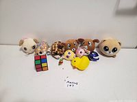 Full view of all plush toys and toys including the Rubik's cube and small figurines arranged on a white surface