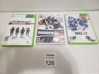 Photo of three video game cases: Xbox 360 Flashpoint Red River, Wii Madden NFL 10, Xbox 360 NHL 12 arranged on a white surface.
