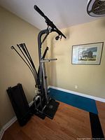 Bowflex machine folded vertically against a wall with resistance rods attached
