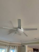 White ceiling hugger style 5-blade ceiling fan mounted on ceiling in living space.