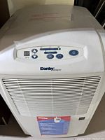 Front view of white Danby Designer dehumidifier with control panel on top showing buttons and branding.