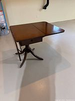 Duncan Fife pedestal dining table with one folding leaf raised showing the drawer underneath