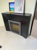 Photo showing the electric fireplace from a side angle, highlighting the wood case with espresso brown/black finish and the silver-colored removable insert.
