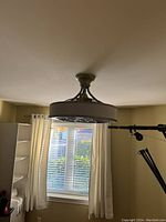 White enclosed ceiling fan mounted on ceiling with visible metal grille and LED light inside.