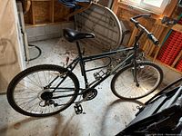 Left side view of the Nishiki Apache mountain bike showing frame, saddle, tires, pedals, and gear system.