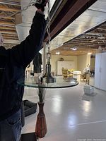 Pendant light shown hanging from chain, giving a side view of glass shade and metal fittings in a room with unfinished ceiling.