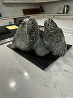 Front view of the soapstone sculpture showing two walruses side by side with detailed features, sitting on a black book on a white kitchen countertop.
