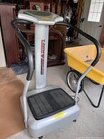 Front view of the silver and black T-zone vibration machine with foot platform and handrails.