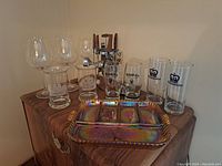 Full lot of barware including glasses, cocktail shaker with utensils, and serving plate.