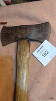 Close-up front view of the rusted double bit axe head and wooden handle.