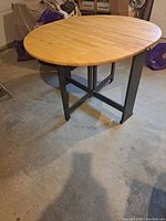 Full table view showing oval wooden top and black metal base.