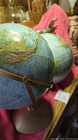 Two globes side by side; one globe has metal biplane model attached at top. Globe details geographic regions including countries and oceans.