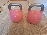 Photo of two pink kettlebells each weighing 8 kilograms with some minor surface wear.