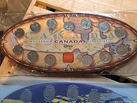 Oval display of 1999 Canadian Millennium coins arranged on a map background.