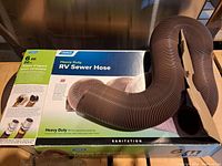 Boxed Camco heavy duty RV sewer hose with 6m/20ft length and hose attached, showing product details on box