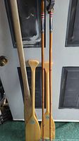 Photo showing two wooden canoe paddles and two vintage ski poles leaning against a door.