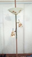 Full view of the vintage pole lamp showing the tall copper-finished pole with a large upward-facing fiberglass shade decorated with botanical motifs, and two smaller adjustable conical fiberglass shades with matching pattern below.