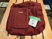 Front view of red Travelon travel bag showing front zippered pocket and logo patch.