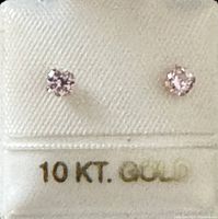 Photo showing two small stud earrings with pinkish tone cubic zirconia stones set in 10 karat gold, with gold stamp '10 KT. GOLD' visible on the display card