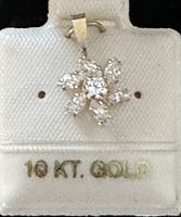 Close-up of 10K gold floral pendant with clear CZ stones on white background showing clarity of stones and gold stamp.