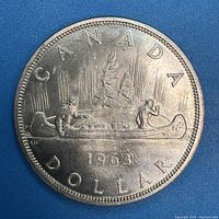 Obverse side of the 1963 Canadian silver dollar coin showing a voyageur and Indigenous person in a canoe.