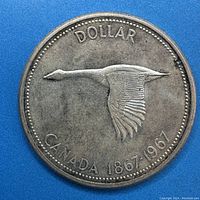 Reverse of 1967 Canadian silver dollar featuring flying Canada goose and centennial dates.