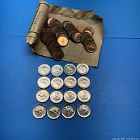 Photo showing 12 Canadian 5-cent nickel coins laid out with a roll of pennies and loose pennies on a brown paper.