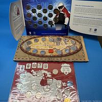 Three coin sets displayed: top with 2010 Vancouver Olympics commemorative coin set in album with thematic blue background, middle Millennium 1999 coin collection with Canadian provinces themed board, bottom 1992 125 Years Canadian Commemorative quarters in protective plastic covering