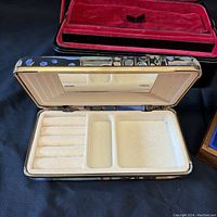 Open rectangular jewelry box with beige compartment interior including ring slots, located on black surface