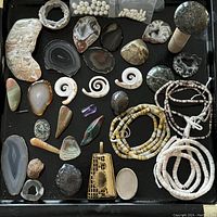 Full view of assortment showing polished and raw stones, shell spirals, beaded bracelets, a mushroom-shaped stone, and gold-tone pendant.
