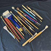 Full lot of 23 assorted paint brushes in different shapes and sizes on black background