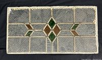 Full view of the rectangular leaded glass window panel showing textured clear glass with green and amber diamond accents.