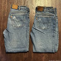 Two pairs of folded Levi's blue denim jeans with Orange Tab labels shown from the back, illustrating the leather waistband patches and back pocket stitching