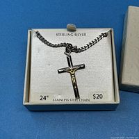 Sterling silver cross pendant with gold-tone crucifix on a 24" stainless steel chain, displayed on a white card inside a box.