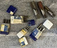 Multiple threading taps laid out with original boxes showing sizes and types, some taps visibly used or rusted at the cutting edges.