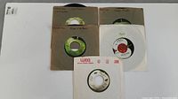 Five John Lennon Plastic Ono Band 45 RPM vinyl records in original paper sleeves, labeled with song titles including Cold Turkey and Power to the People.