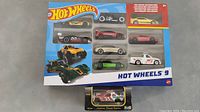 Photo of the 9 Hot Wheels cars in one box and 1 boxed Revell Racing Car below it