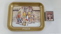 View of the Coca-Cola metal tray and one pack of Coca-Cola trading cards beside it