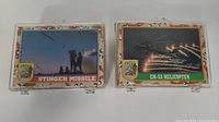 Two sealed plastic containers of Desert Storm trading cards, one featuring Stinger Missile and CH-53 Helicopter cards.