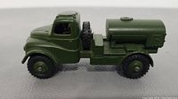 Side view of green die-cast army water tanker toy truck showing the cab, water tank, and spare tire mounted between them.