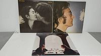 Photo showing all three John Lennon album covers including Double Fantasy, Imagine, and a third album with two men at a dining table.
