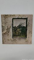 Front cover of Led Zeppelin IV album showing iconic artwork of man carrying sticks with worn, cracked plaster background