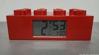 Front view of the red Lego digital alarm clock showing LCD time 21:53 and alarm set at 1:00.