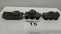 Front view of three vintage Lesney military vehicles showing tank, armored car, and carrier in green paint.