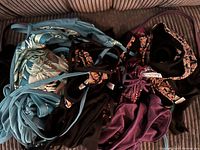 Photo showing folded bikinis in assorted colors including light blue, black, purple, and mixed floral/leaf patterns.