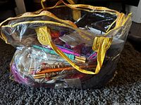 Large transparent bag with yellow handles containing many Asian themed decorative and fabric items