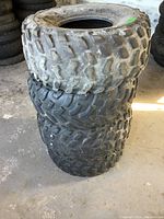Stack of four used ATV tires showing tread patterns and wear.