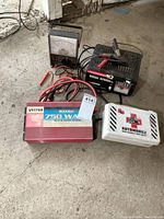 Photo showing all items: Motomaster battery charger, analog multimeter, Vector 750W inverter, and white first aid kit case.